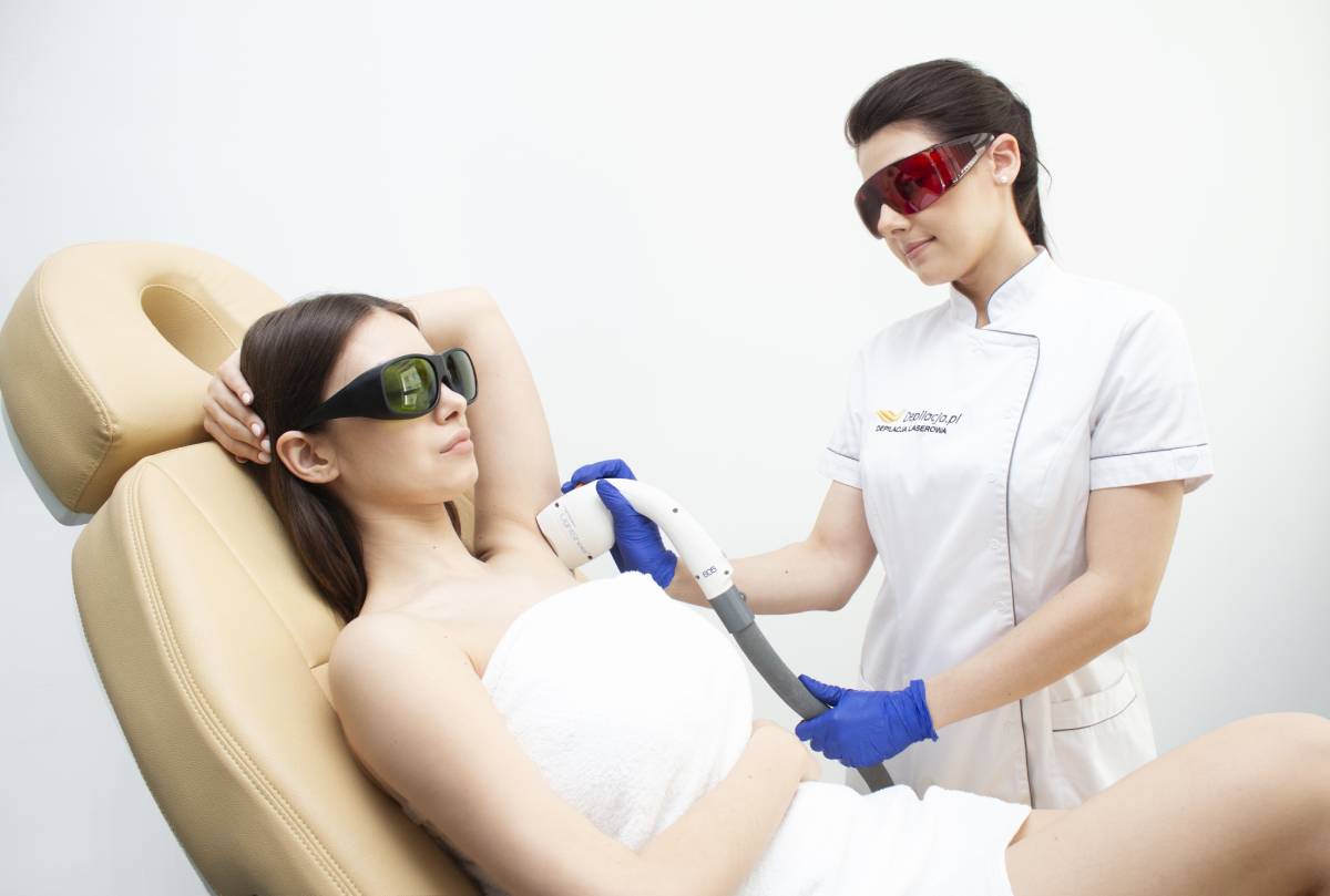 Kosmetolog przeprowadza zabieg depilacji laserowej pach.