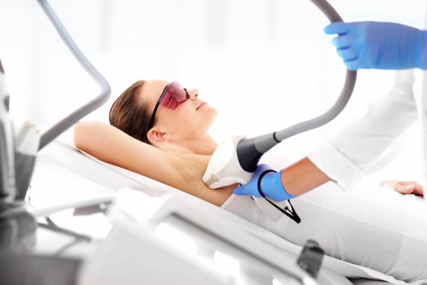 kobieta leżąca na łóżku podczas zabiegu depilacji laserowej
